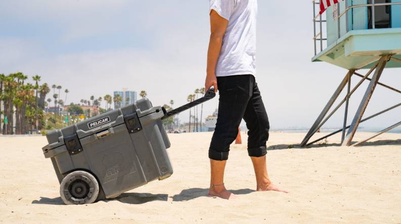 Person dragging a small rolling cooler with beach wheels