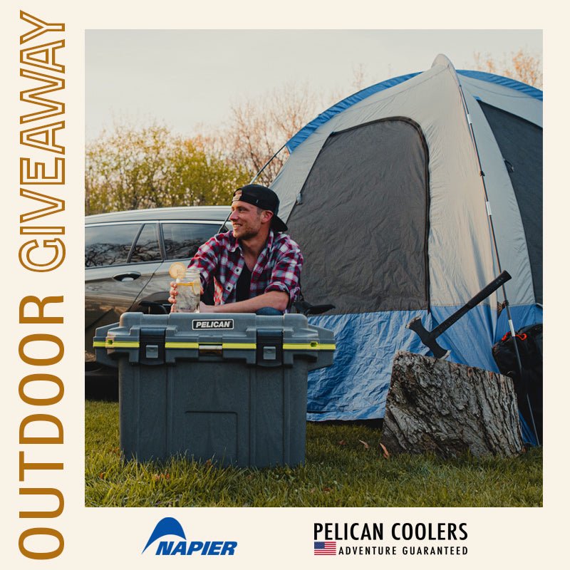A man sits at his campsite. There is a Pelican 50QT Elite Cooler in front of him, and a Napier Outdoors Sportz Dome-to-Go tent behind him. 