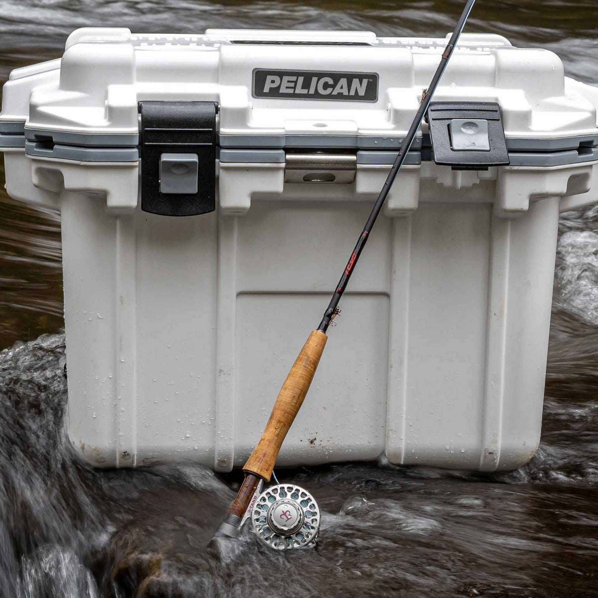 White / Grey Pelican Elite Cooler in stream with fishing rod